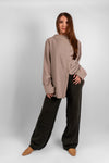 Woman wearing a long sleeve asymmetrical blouse in luxurious premium fabric, tunic length, modest fashion style.
